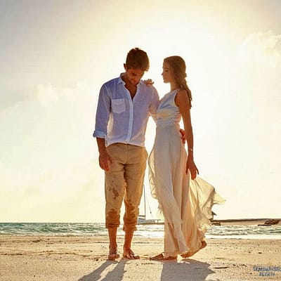 Paar in leichter Brautkleidung auf einer Sandbank auf den Malediven. Kurz bevor die Sonne untergeht