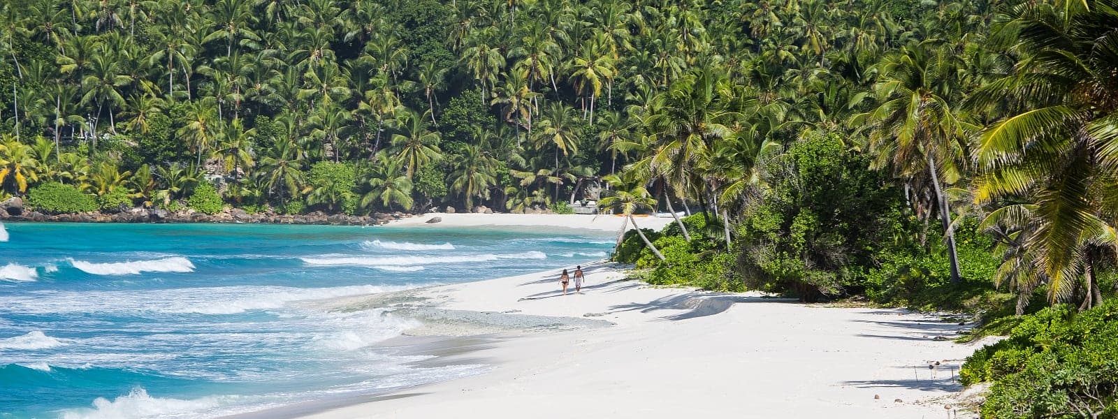 Ein Paar spaziert am leeren Strand der Insel North Island auf den Seychellen
