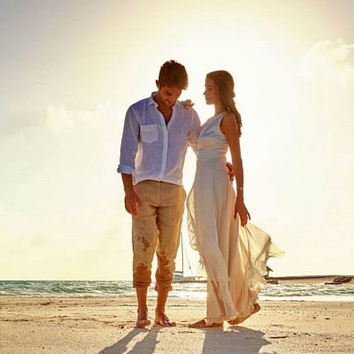 Paar in leichter Brautkleidung auf einer Sandbank auf den Malediven. Kurz bevor die Sonne untergeht